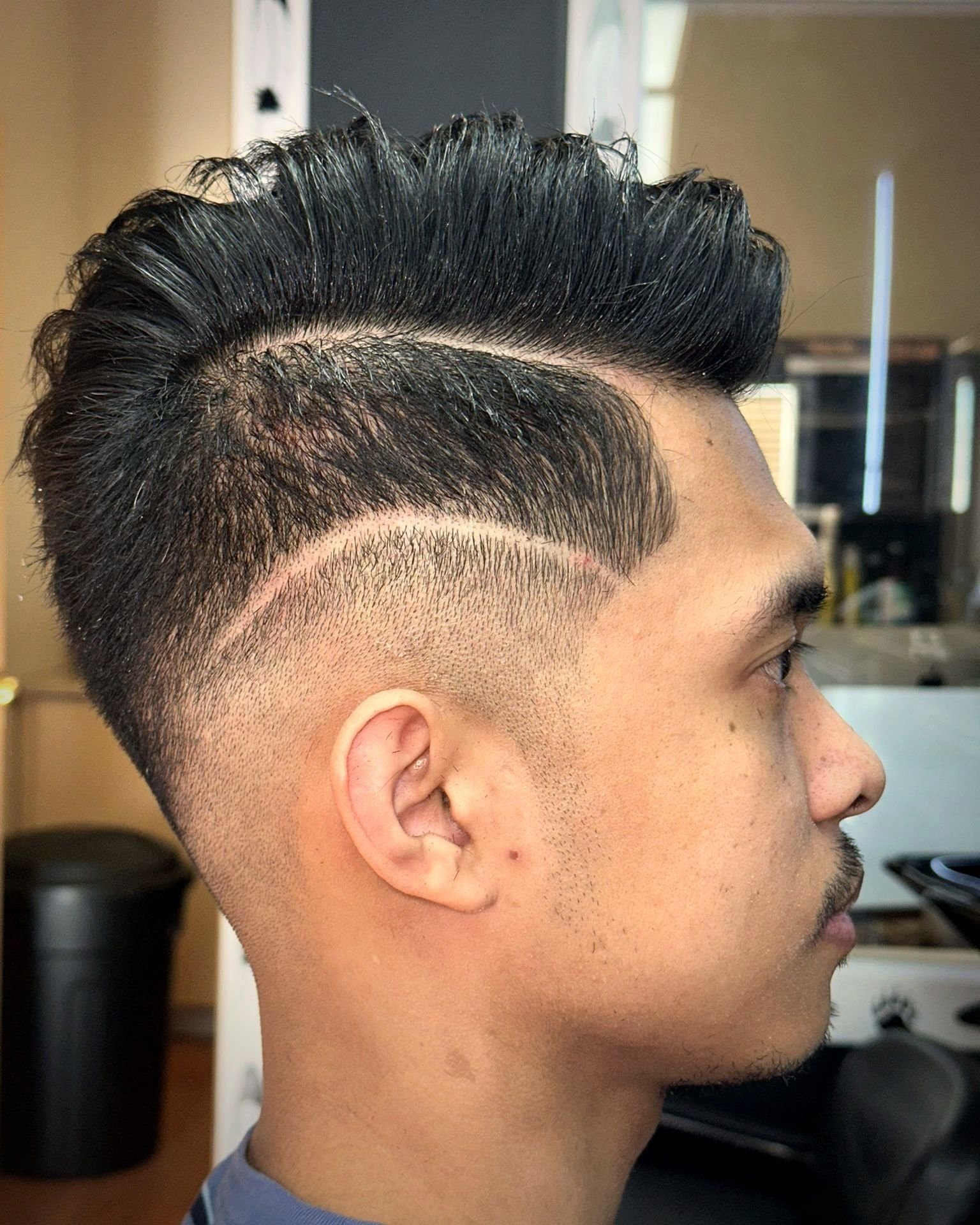 Textured pompadour with a fade and a shaved part line, BC Barber Shop
