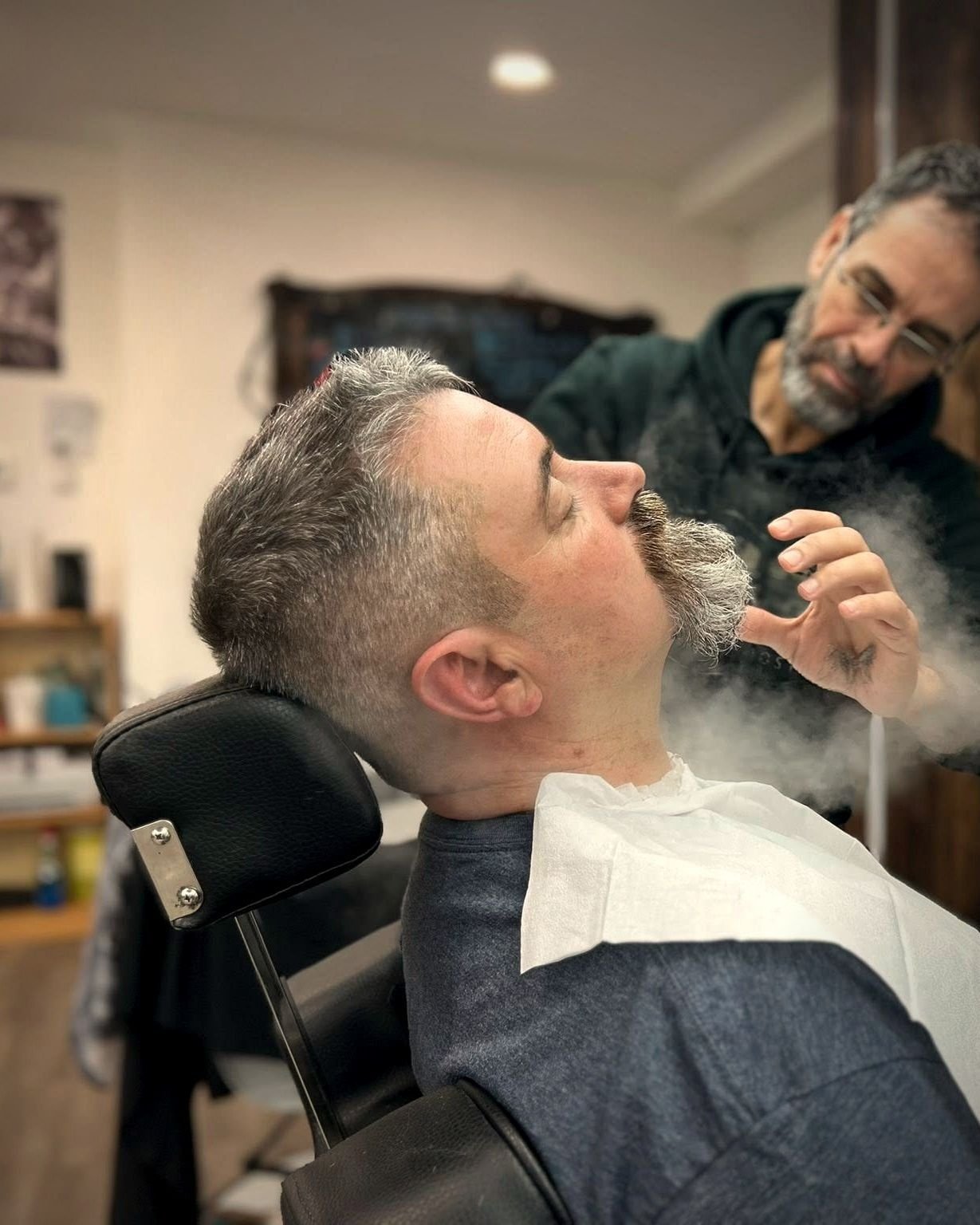 Barber steaming a client's beard during a hot towel treatment, BC Barber Shop